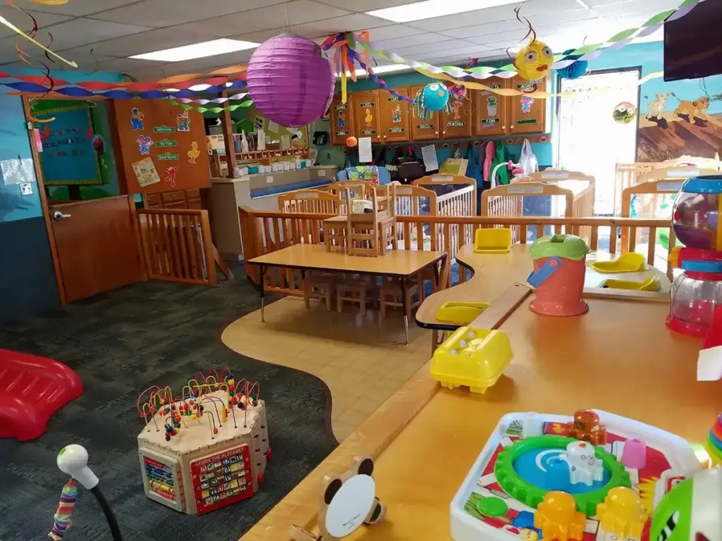 Colorful children's playroom filled with tables, chairs, toys, and festive decorations.