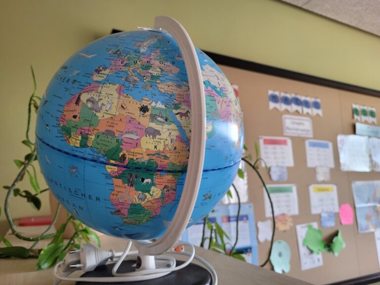 elementary school students studying a globe together in a classroom